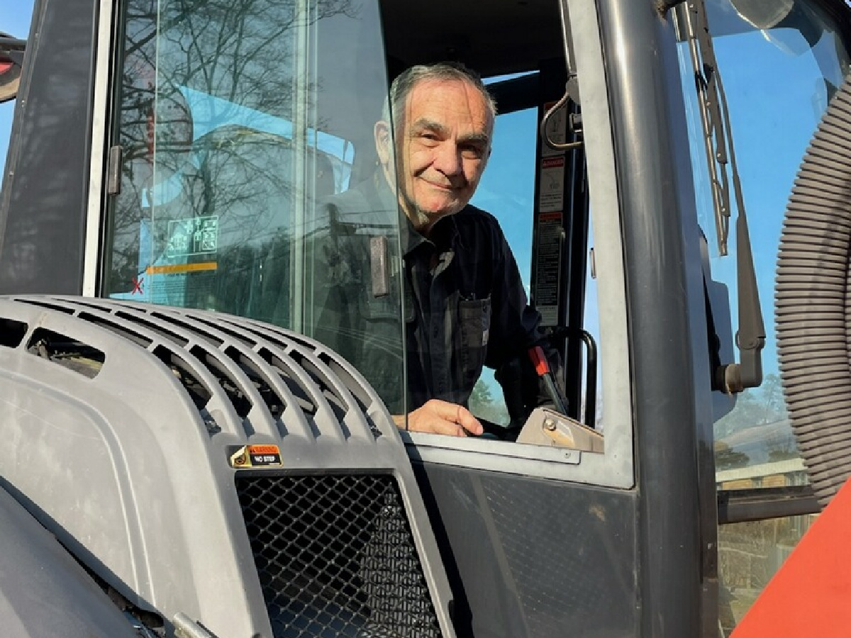 Dr. Kurti in heavy equipment, smiling from the cab